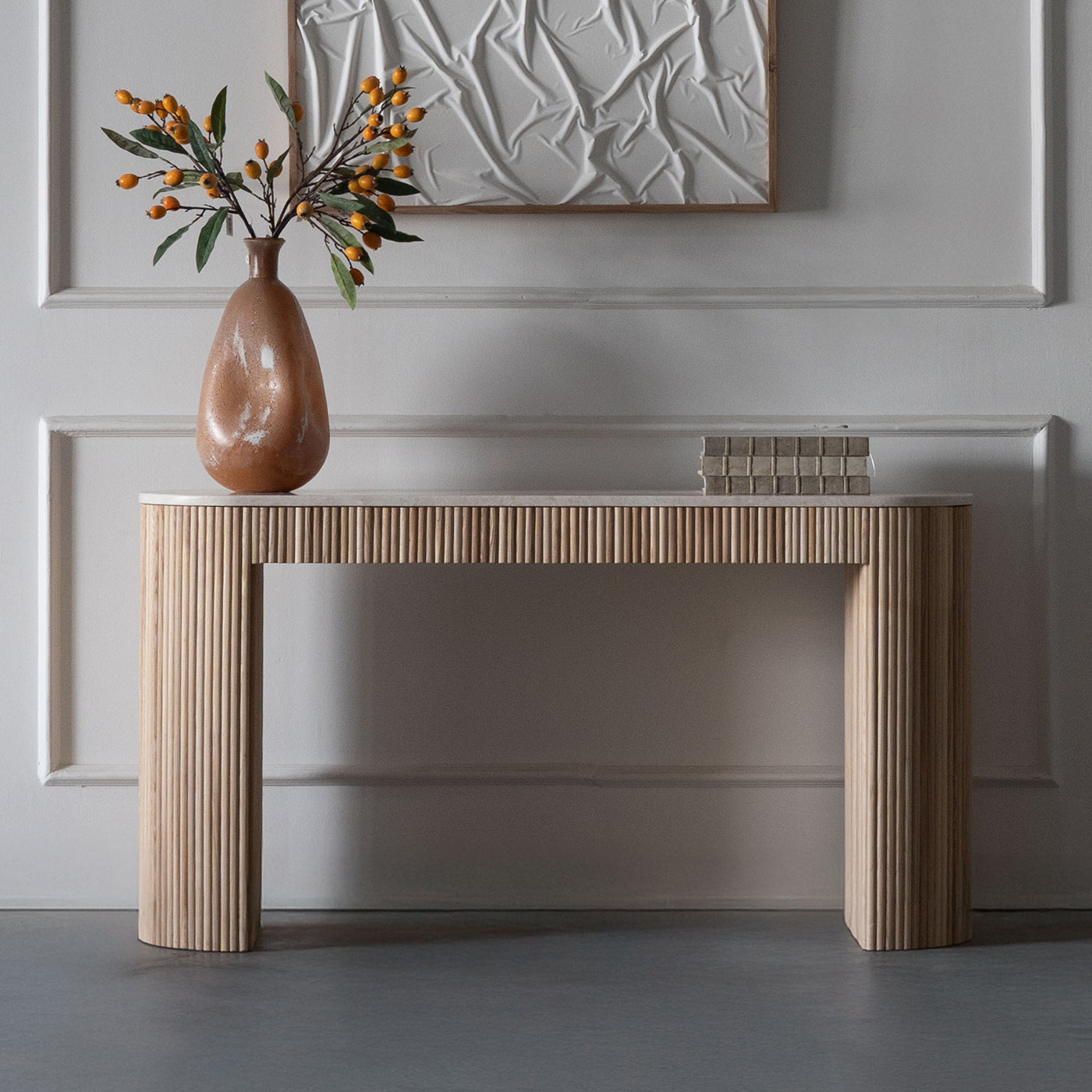 Wooden console table with a vase and decorative items against a neutral wall.
