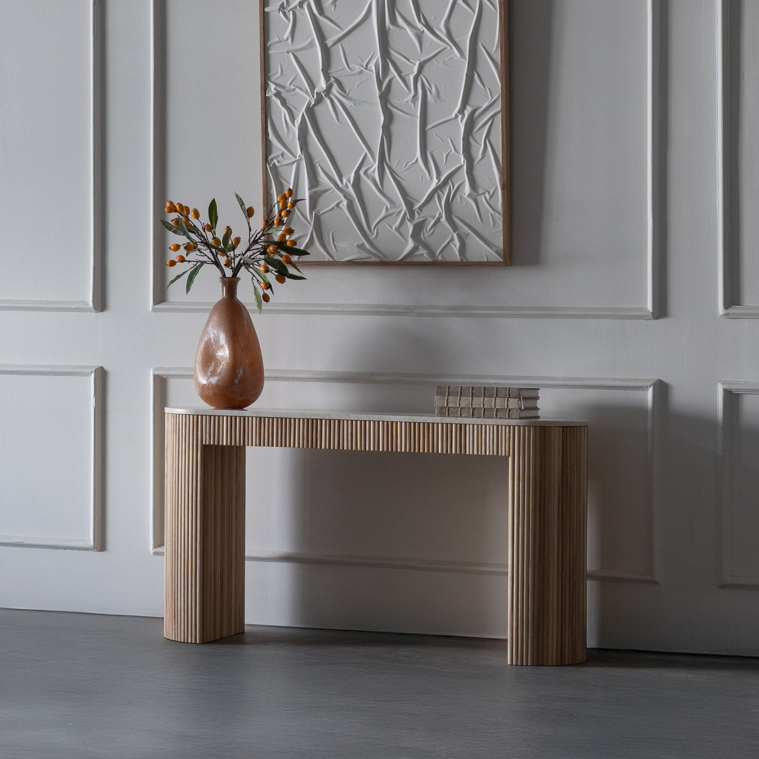Modern console table with a vase and decorative items against a textured wall.