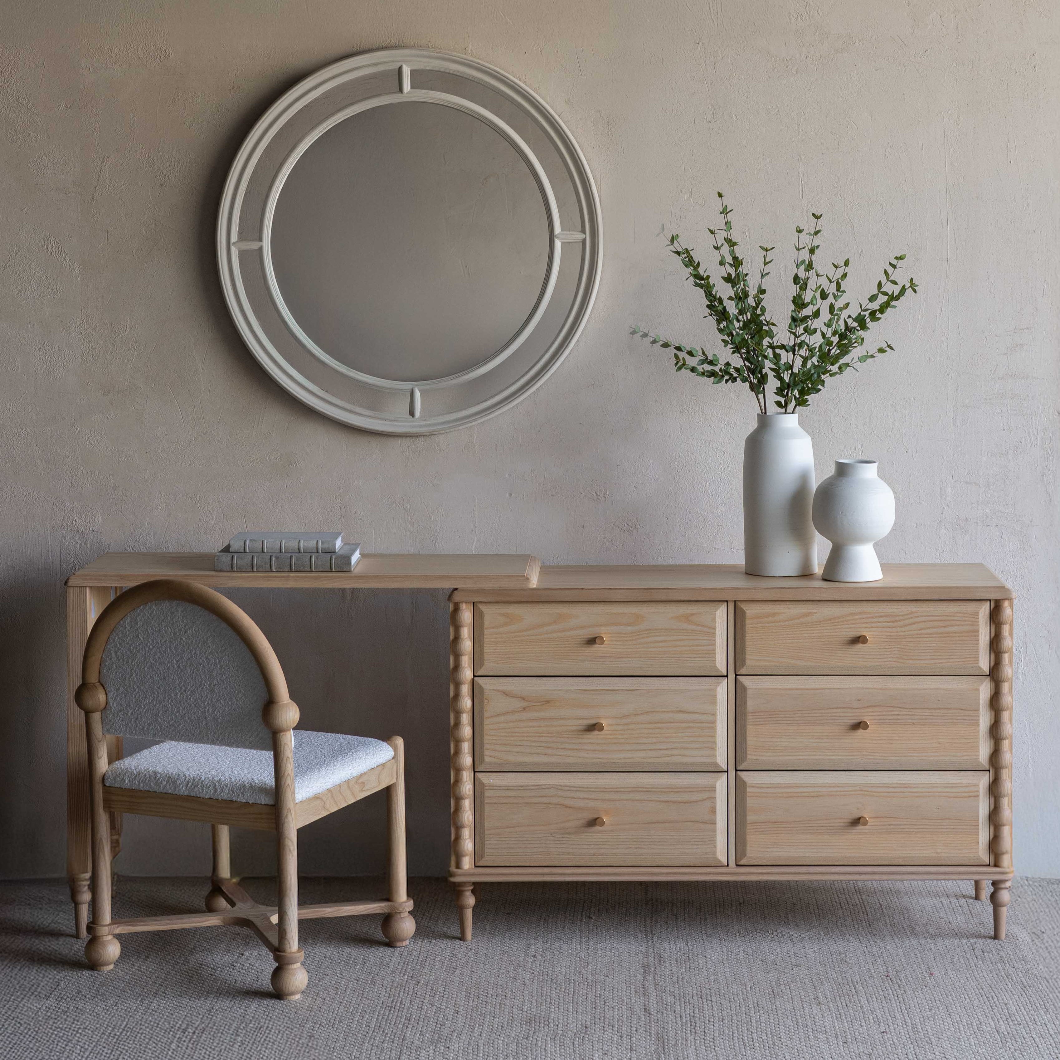 Light wood dresser with mirror and chair against a beige wall