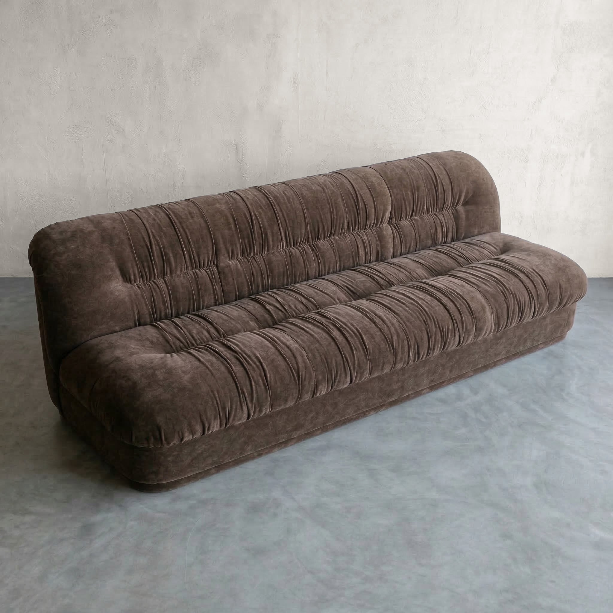 Brown sofa in a minimalistic room with a plain wall and floor.