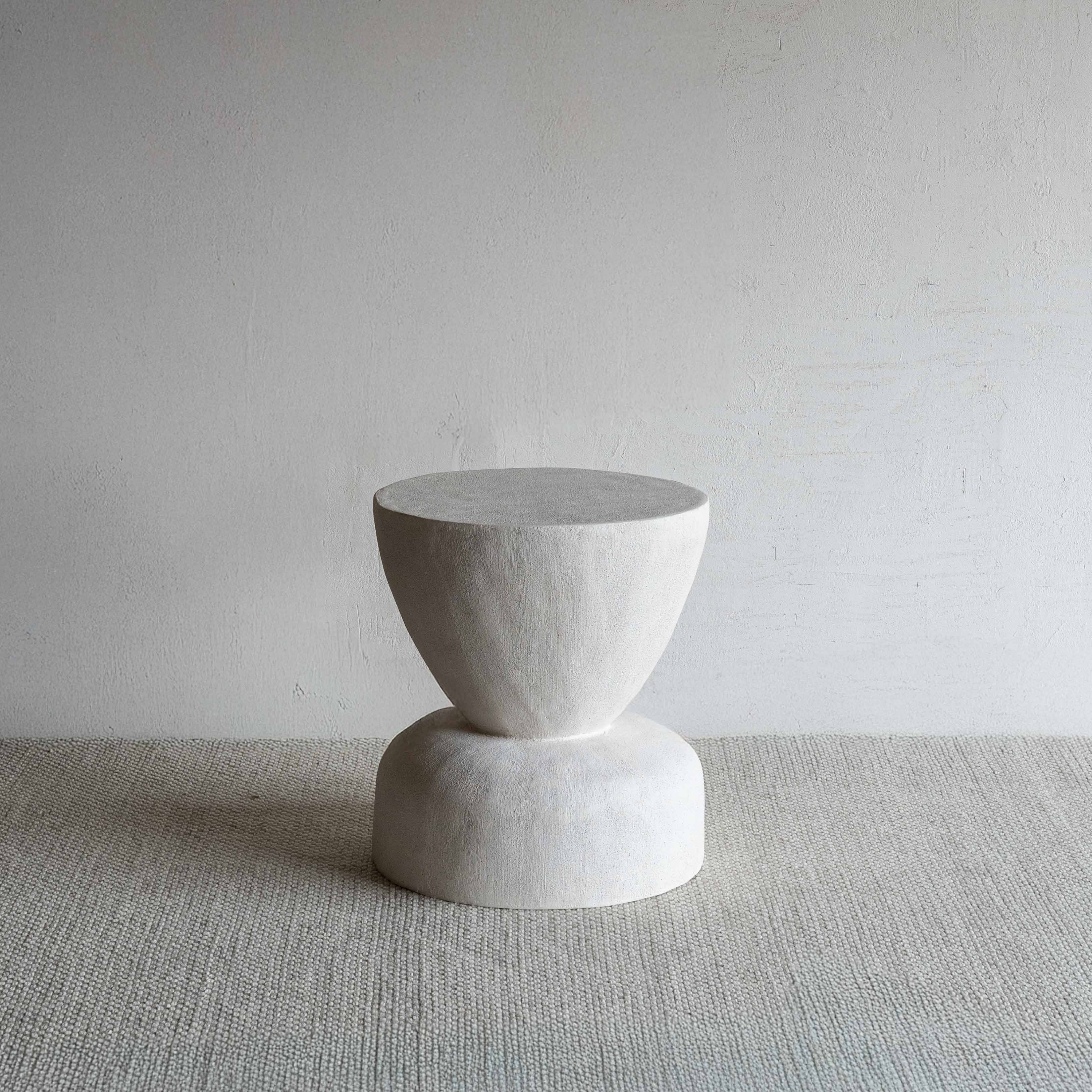 White stone stool on a textured surface with a plain background