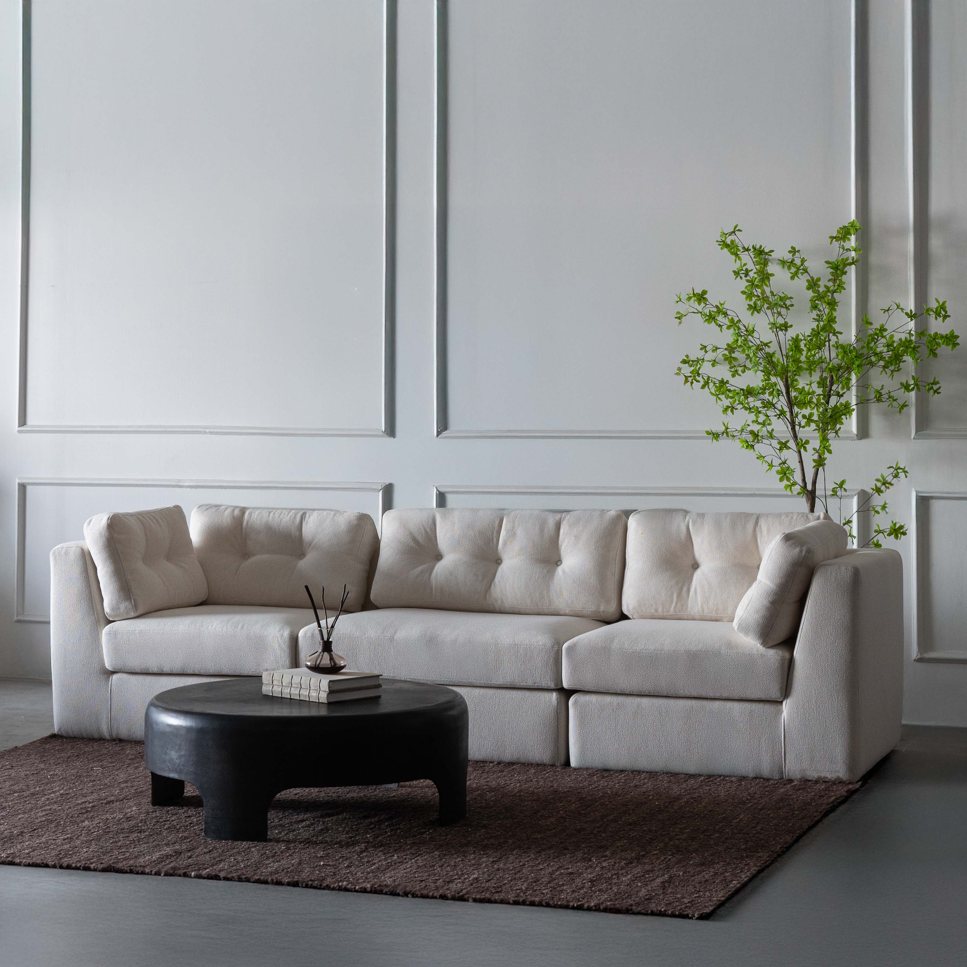 Beige sectional sofa in a modern living room with a black coffee table and a plant.