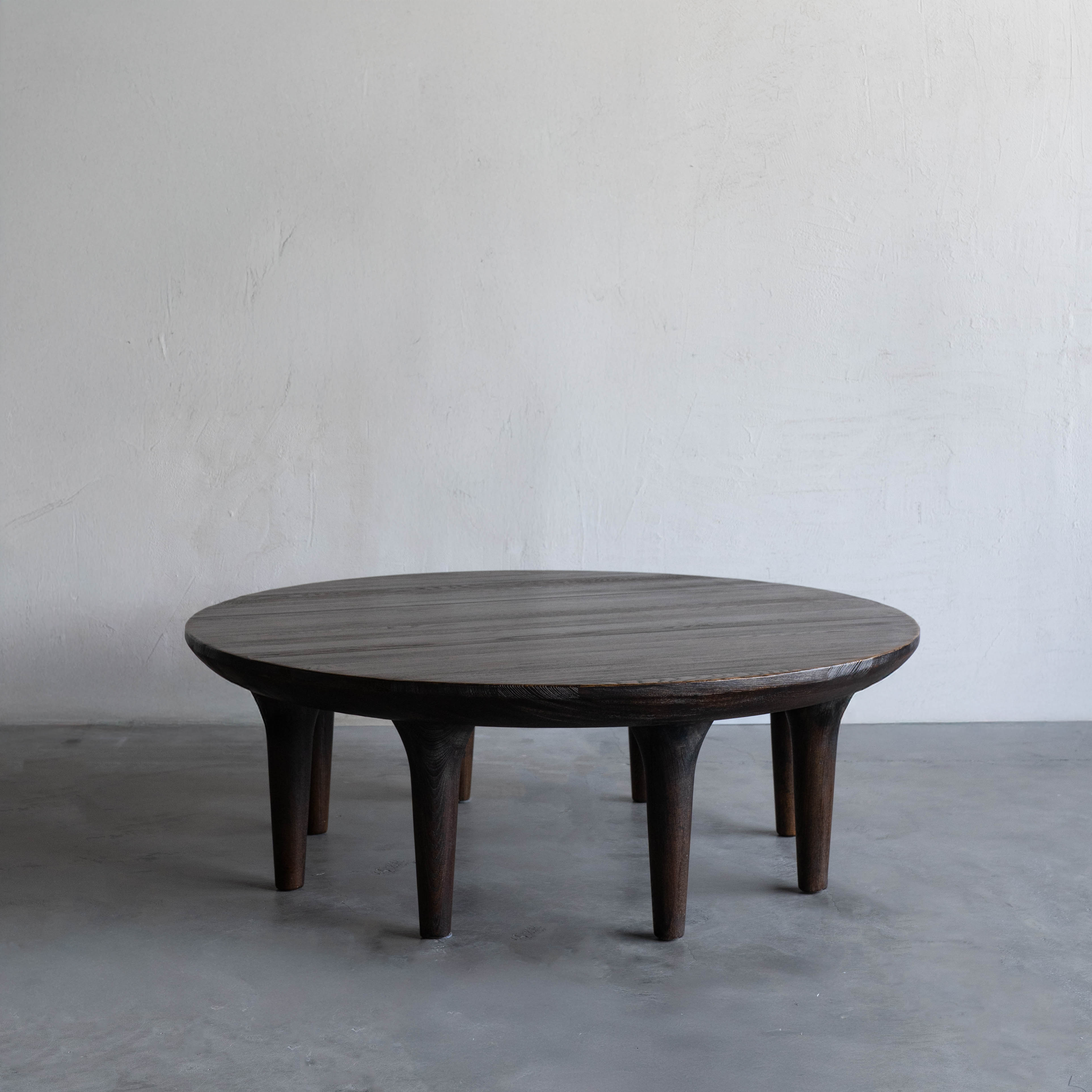 Round wooden table against a plain wall