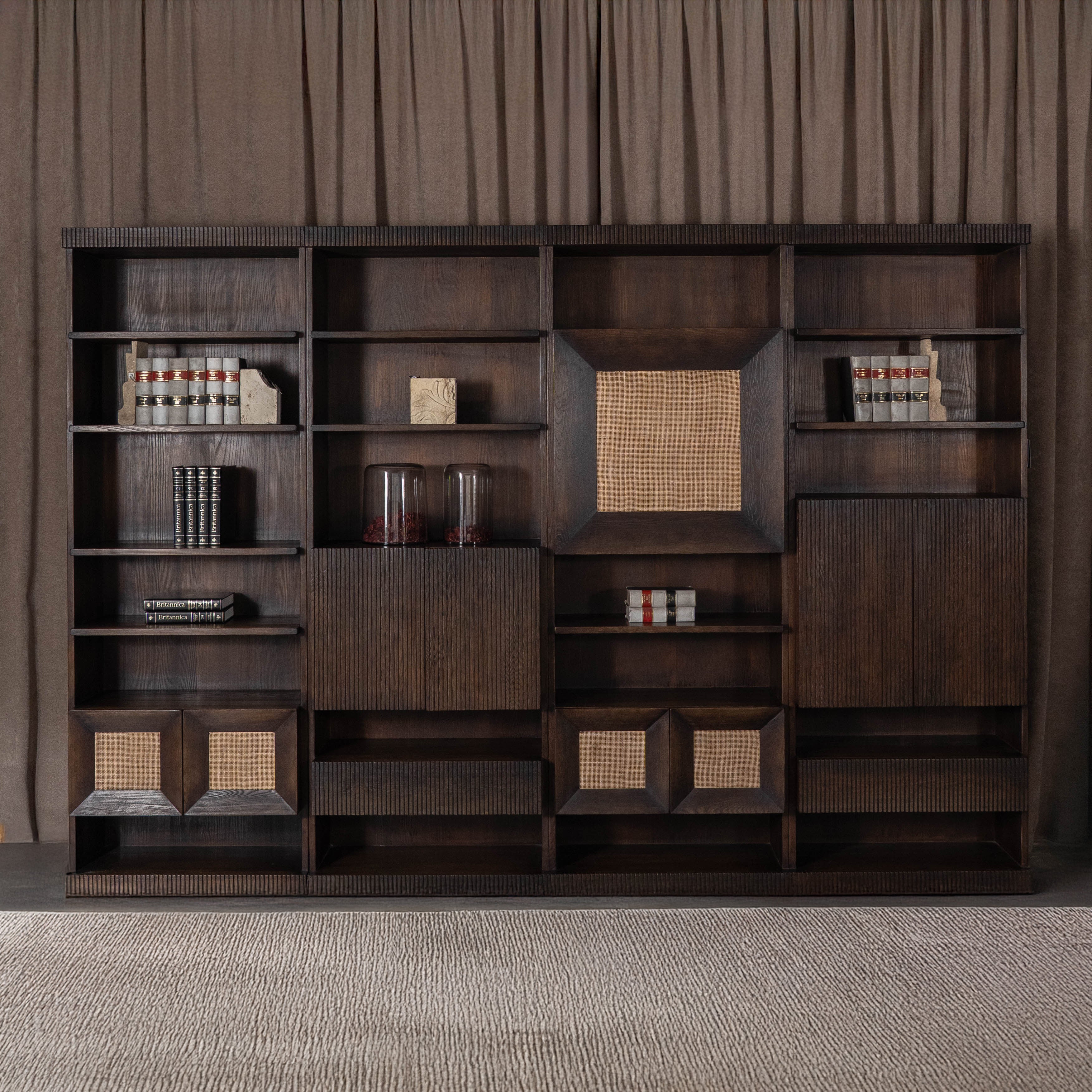 Dark wooden bookshelf with decorative items against a brown curtain background