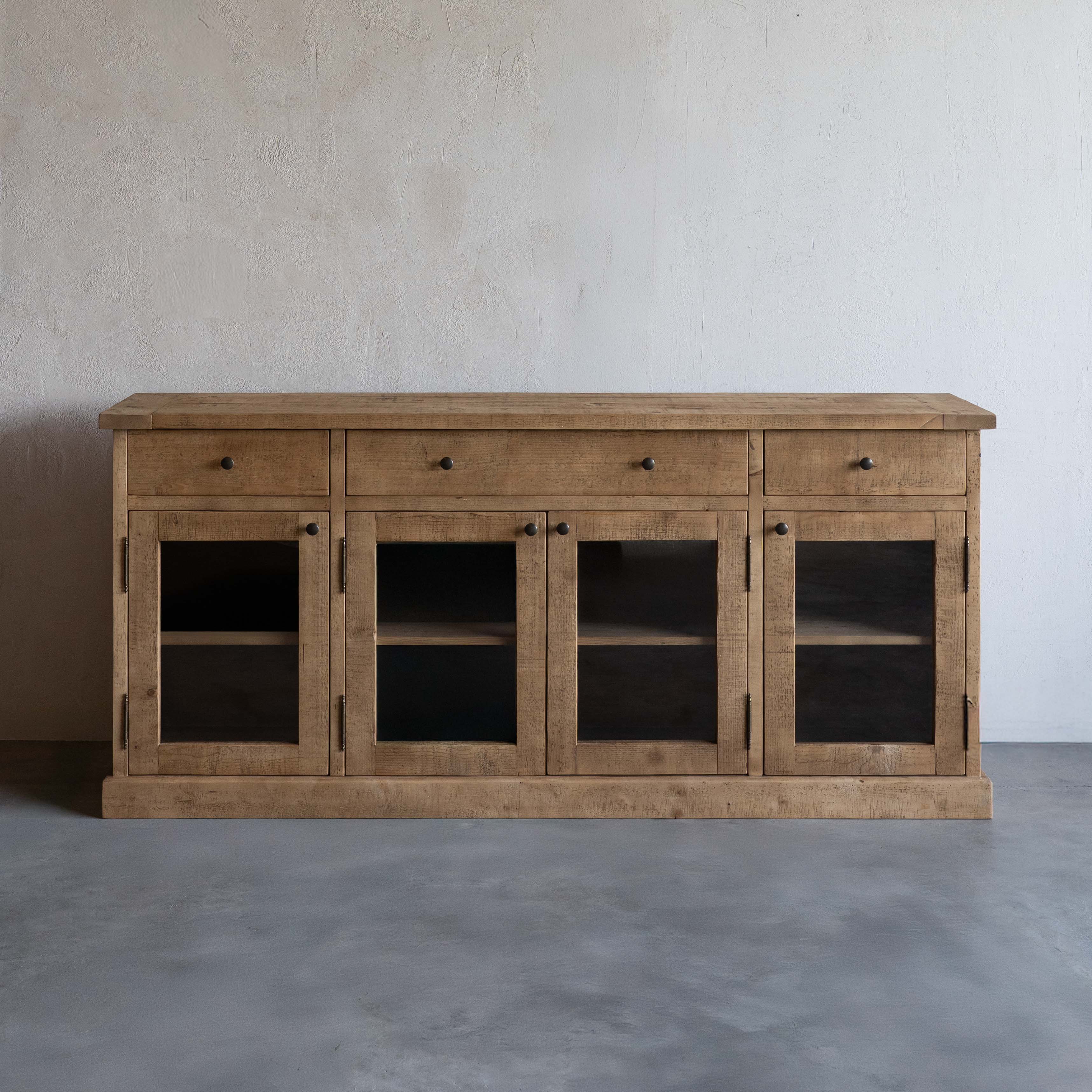Wooden sideboard with glass doors against a plain wall
