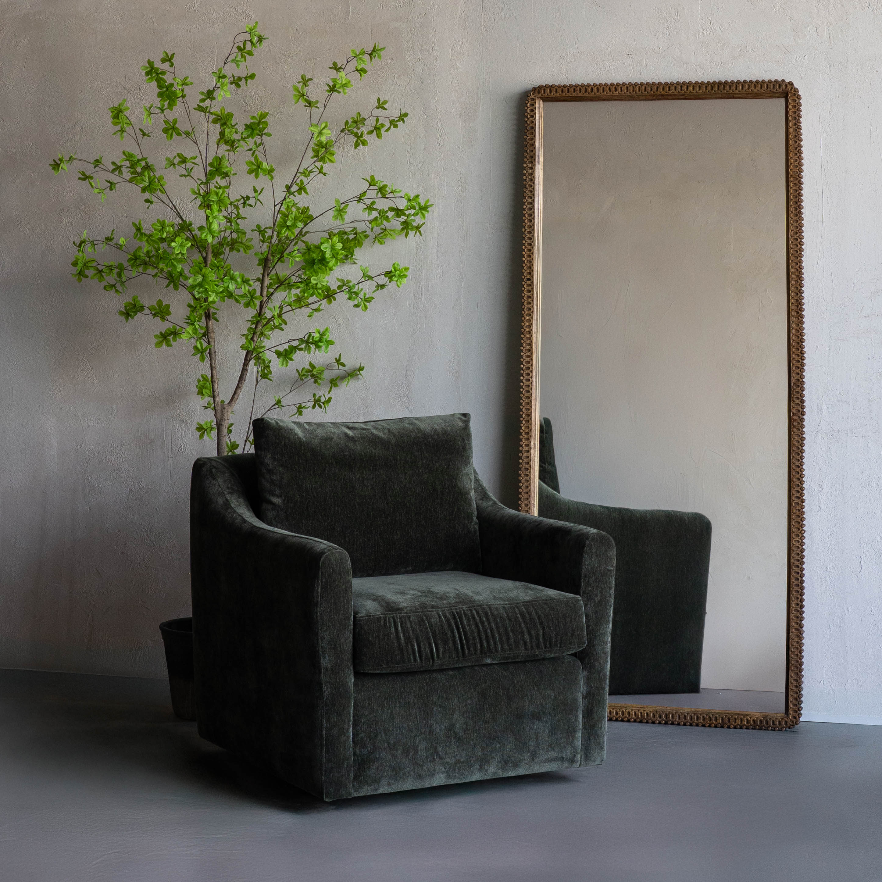 Gray armchair with a plant and mirror in a minimalistic room