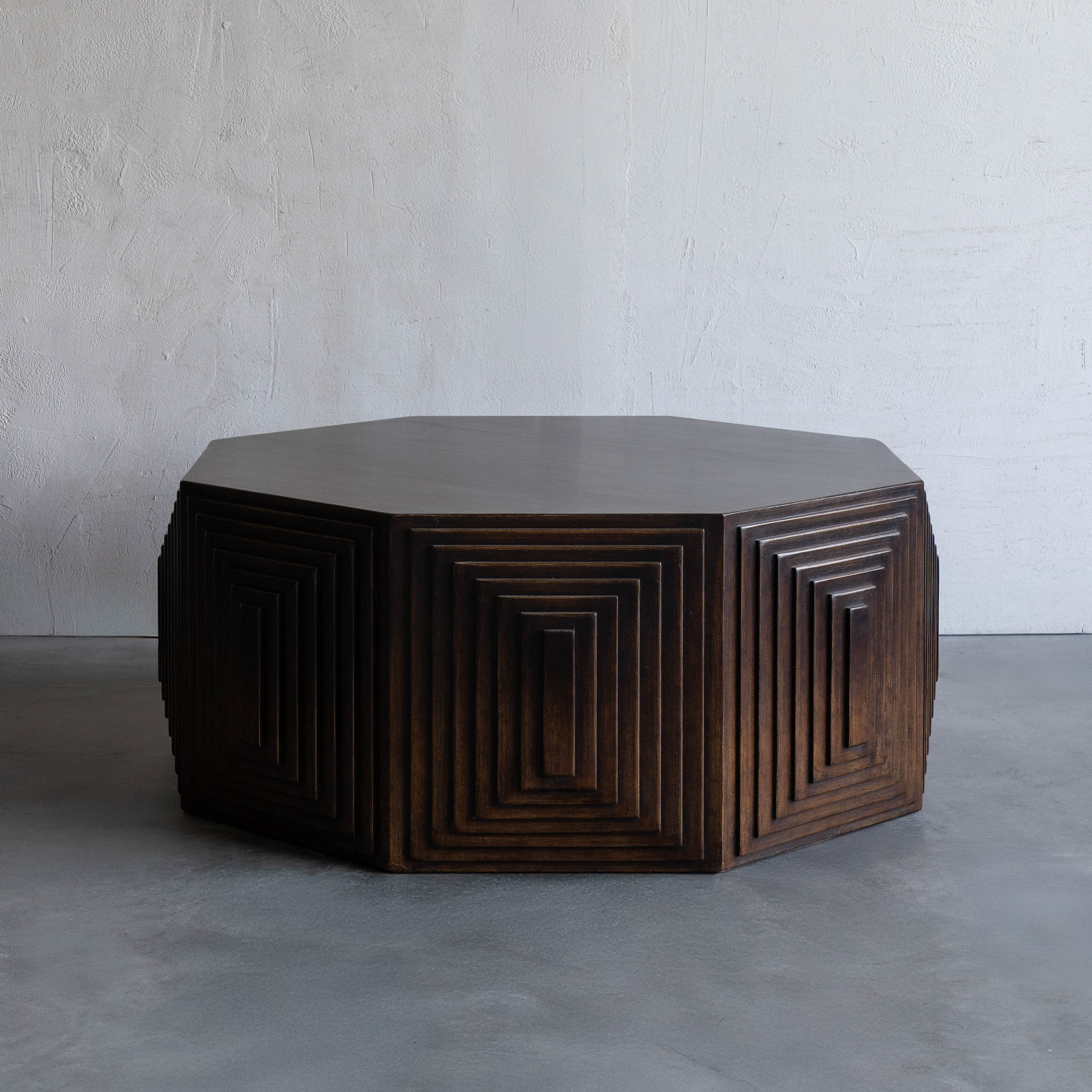Wooden octagonal table with geometric design on a gray floor and light gray wall background