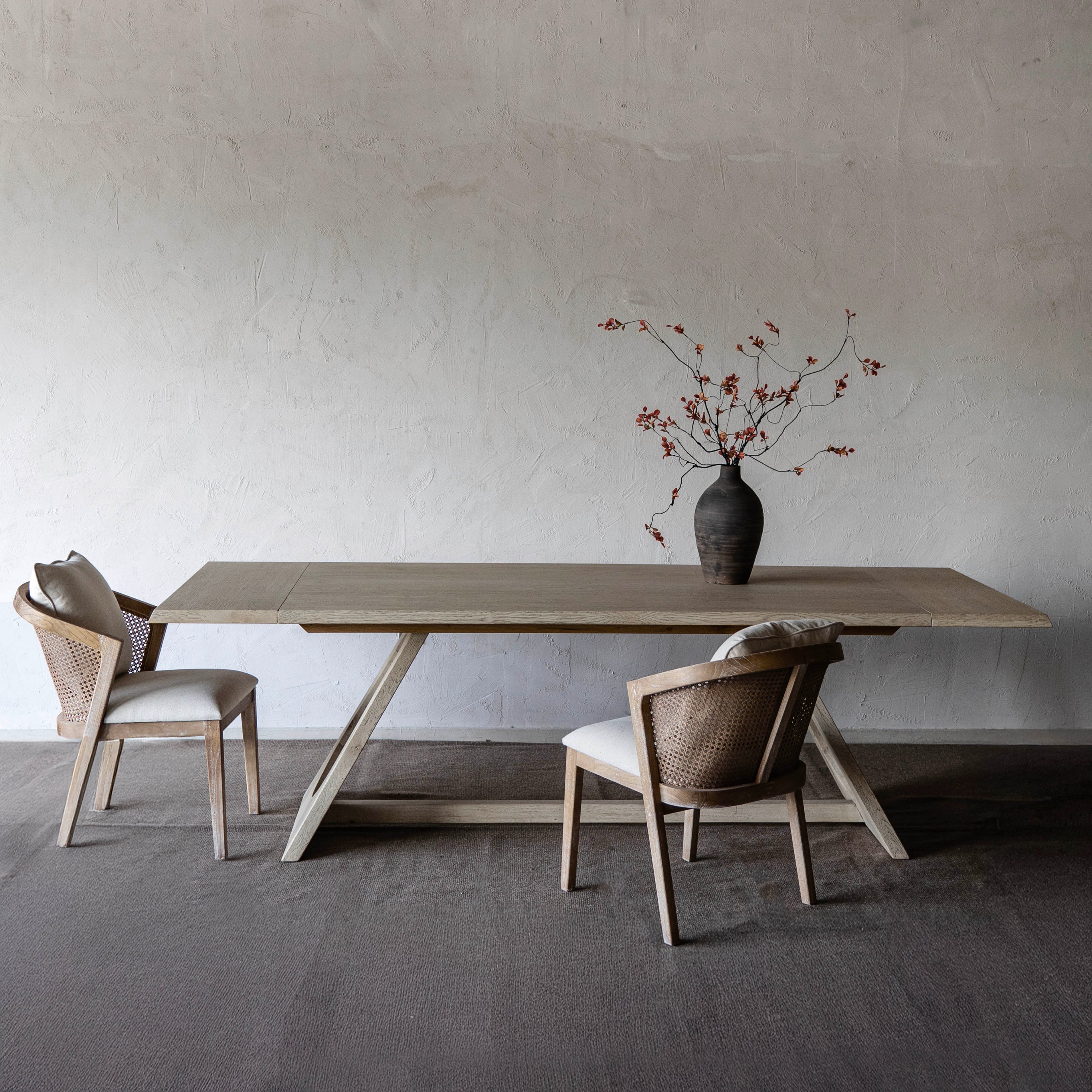 Dining table with two chairs against a plain wall